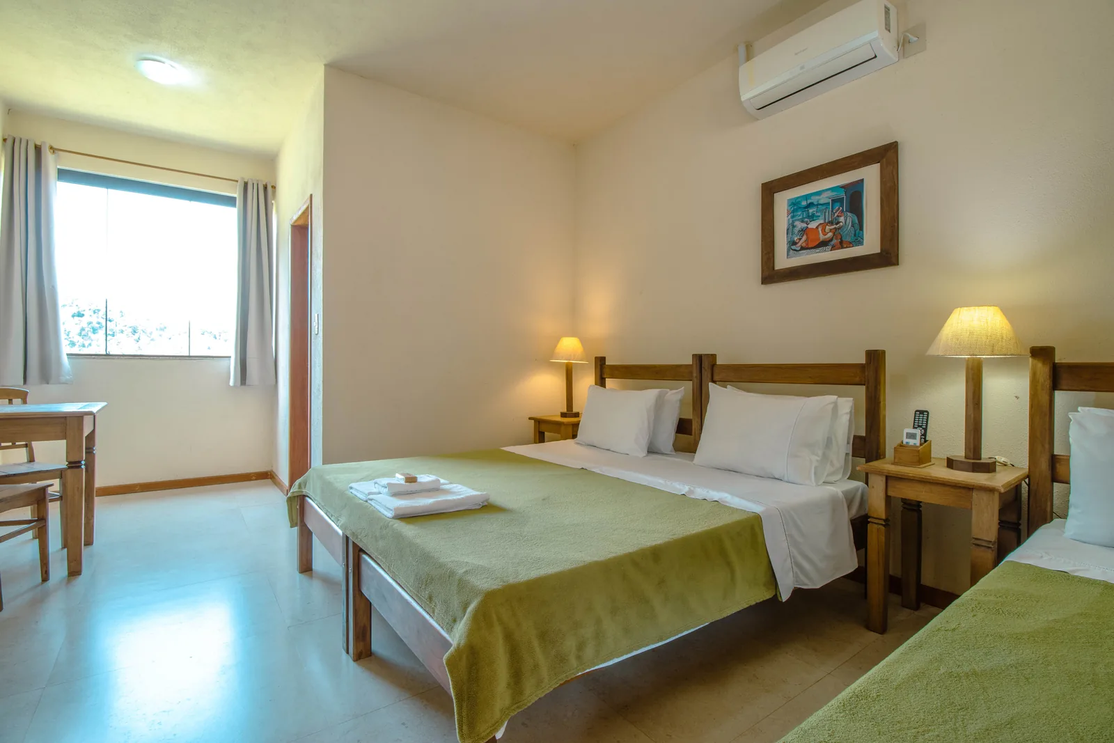Suíte do Hotel Fazenda Minas Real com as camas arrumadas, abajures acesos e a janela aberta para o verde