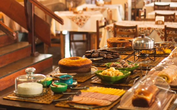 Buffet do café da manhã montado, com o salão do restaurante ao fundo