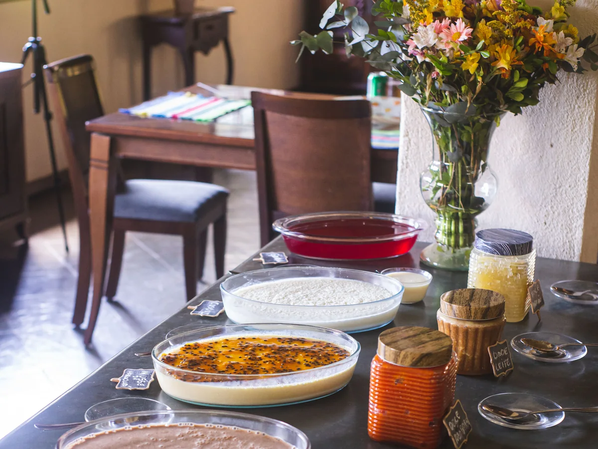 Mesa de doces caseiros do lanche da tarde, com mousse de maracujá, arroz doce, doce de leite e goiabada