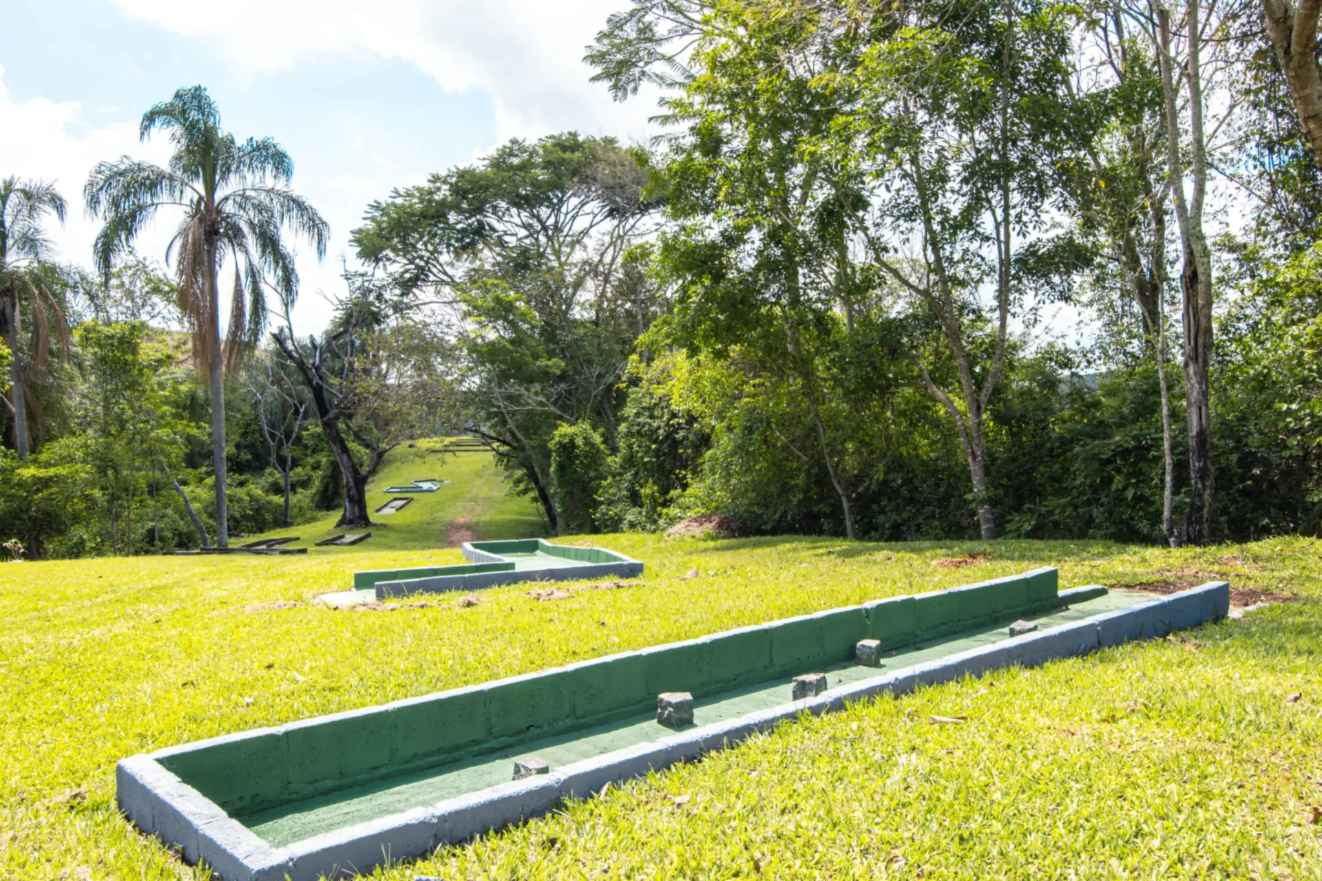 Pistas de minigolfe descendo o gramado do Hotel Fazenda Minas Real, entre as árvores